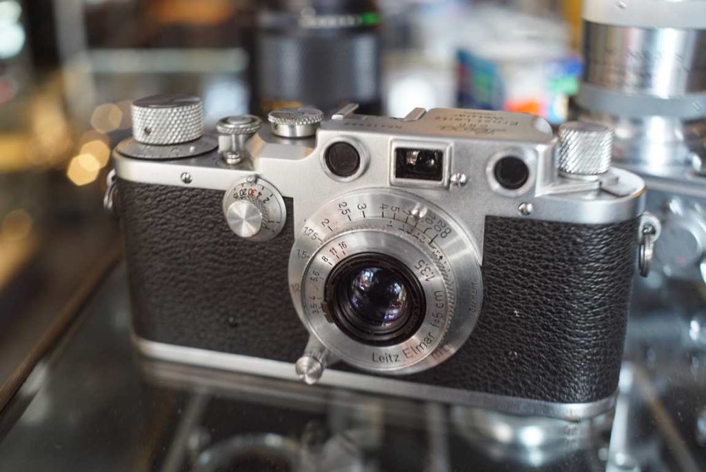 Leica IIIc camera in very beautiful condition, with matching 50mm elmar lens. Slow speeds are not sounding too healthy and are probably not accurate or consistent. The camera is sold as collectors item since the topplate looks so clean and good. Some very light usermarks but the plate around the Leica logo looks perfect. Light marks on bottom plate. The lens is super clean, no coating damage or scratches. Very faint haze inside like always, but this lens will be a perfect user on your LTM or M camera with adapter. As far as we can see there are no holes in the shutter curtain, this will most likely be light tight. Fast speeds are not tested on our machine, but might be perfectly usuable after your first film tests.