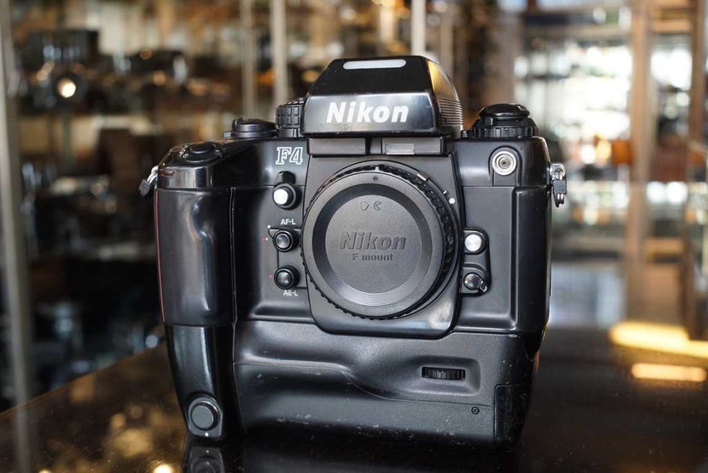 Here we have a Nikon F4E which is a F4 with MB-23 motor drive. The camera is in good working condition but does have regular signs of use, mostly around body edges and the motor drive lower body. The camera was machine tested and found to be working accurately on all speeds and the lightmeter is also accurate. The finder has no LCD leakage, this is quite special for the F4 in this day and time. A excellent user camera for the vintage nikon lens user due to the many lenses you can use on this up to the AF-D era. The camera features good AF but of course still is great for MF nikkor glass due its AI-S coupling which was deleted off later models.