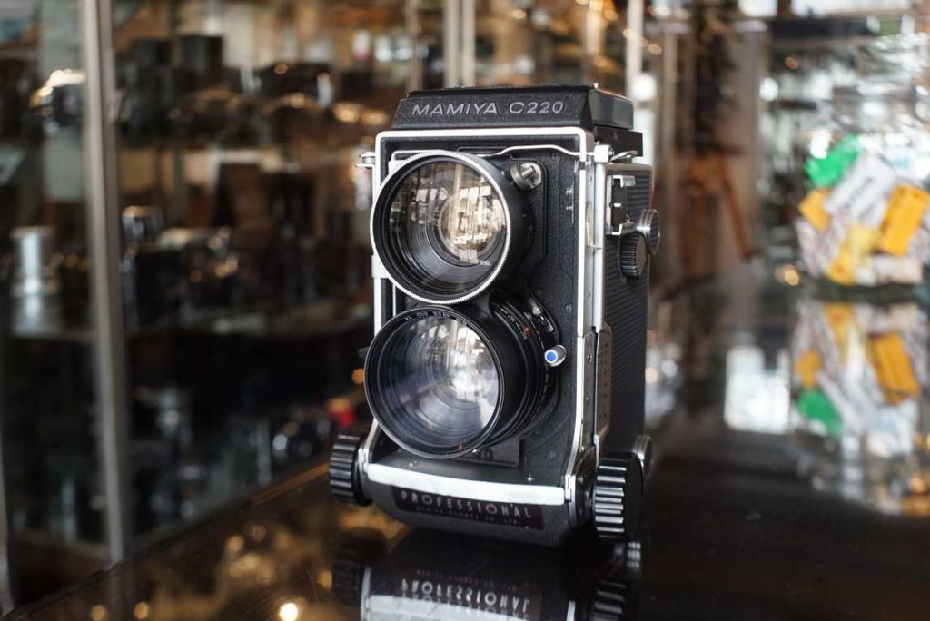 This Mamiya C220 TLR camera comes with matching 65mm F/3.5 lens. The 65mm F/3.5 is a perfect starter lens for this system, works out to be around a 35mm lens on 35mm film. A nice wide standard suited for many applications. The C220 and C330 are of course a bit larger than common TLR models but you get so much more functionality since you have the bellows focusing system and interchangable lenses. This kit comes with the modern generation blue dot lens with improved shutter. The kit has been machine tested and all the speeds work perfect. The aperture ring works as intended. Focus is smooth and the bellows are light tight and healthy. Some dust on the focusing screen as always but nothing that influences your ability to focus. Cosmetic wise the kit is in outstanding condition as well, was definately taken care off by the previous owner.  Note: there was a tiny dent in the taking lens filter thread. We have repaired this back into shape, its not perfectly round but now takes 49mm filters again. New seals installed inside the body.