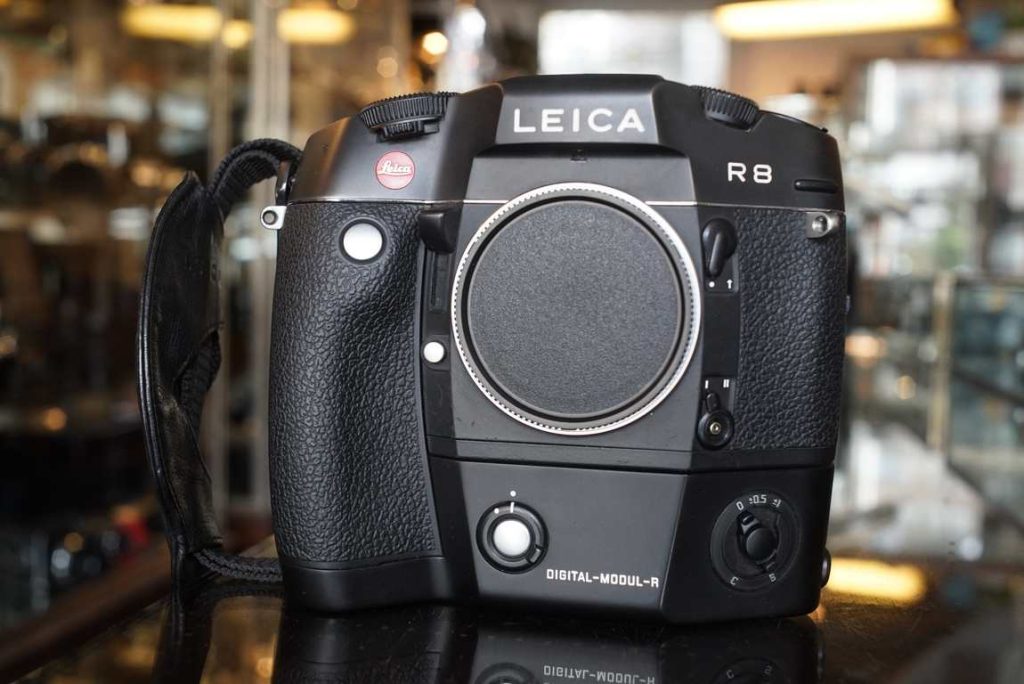 Not your typical Leica R8 camera. This one is fitted with the Digital-Modul-R. This back transforms the R8 into a digital camera with APS-H sized CCD sensor. This sensor is super sought after nowadays since its capable of producing slide film like colors and contrast, a true digital classic like the M9 rangefinder. The Modul-R usually has some battery related issues, thats why we have serviced the battery. The pack has been rebuilt with new rechargable cells inside. The DMR was then tested on our machine and works as intended on all aspects. No sensor damage on filters in front of the sensor. No LCD bleeding and also no physical LCD scratches on the rear. Buttons and dails work as intended and feel firm and responsive. The camera is fitted with a wrist strap, special focusing screen for this DMR and comes with the battery charger, new cell battery, additional focusing screen, protective cover for the CCD, connectivity cable, manual. Because of the nature and age of the CCD back we can not provide a warranty on it. The mechanics of the camer and newly celled battery come with a 90 day warranty.