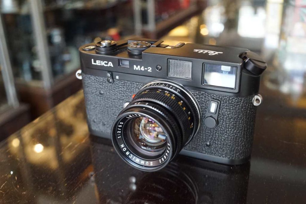 A Leica M4-2 in such a good condition that we decided to sell it directly as-is. All the shutter speeds of the body are well within factory tollerances and will expose film more than perfect. The rangefinder is calibrated well and moves as intended. Framelines are nice and sharp. Framecounter works as intended. Lens focuses very well, not too heavy. No remarks to be made about the optics, very clean glass. Aperture works as intended. A very clean body with just some minimal remarks to be made: leather on right hand side (part you hold the camera) has a small patch in the leather covers. Some light strap wear around the lugs and a tiny dent in the lenshood which is included for free with this kit. Beautiful camera with great lens in very well preserved and good user condition.