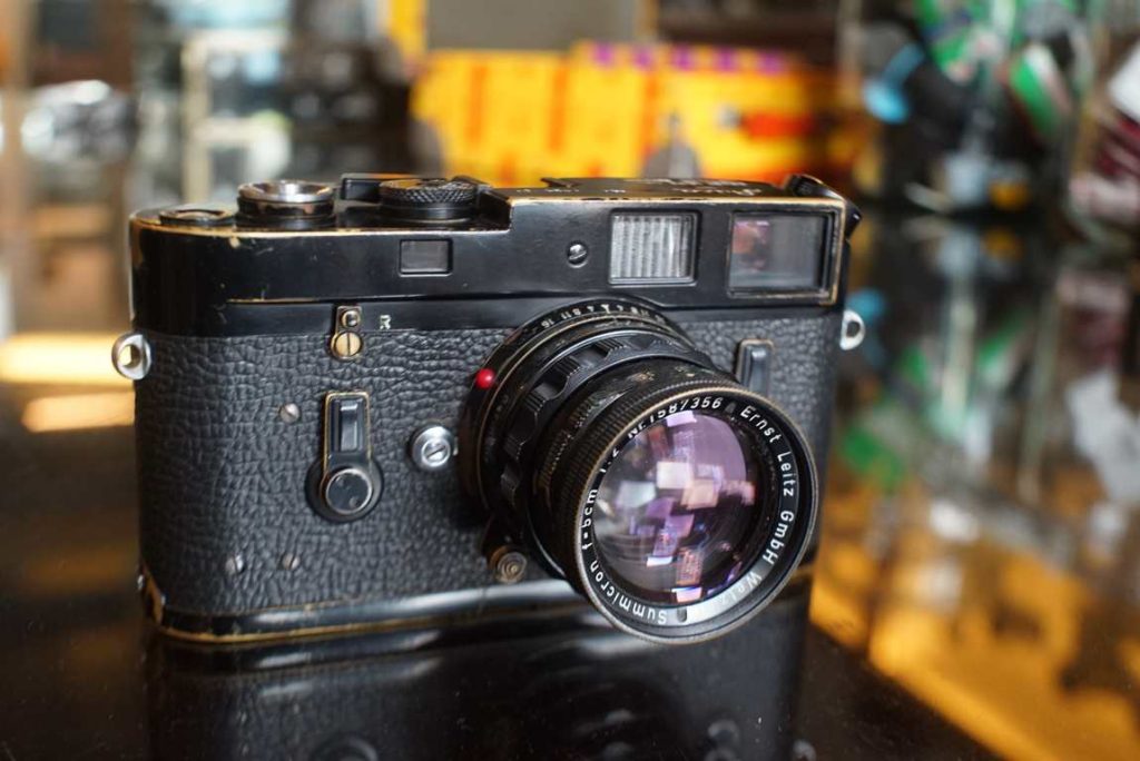 This Black paint Leica M4 body comes from an official batch made in 1969. It comes in original and unrestored condition with the typical patina and brassing to it's black paint parts. without L seal. Obvious marks and few scracthes and a tiny bump to top plate which gives the camera a lot of character. Rare version and highly sought after camera nowadays. The camera comes in a good functional condition. Shutter fires within tolerance at all speeds. sometimes slightly hesistant at slow times. rangefinder well adjusted and bright however we see a bit of haze in the viewfinder. minor overlap of framelines at 50mm. Perfectly usable camera. Rare and sought after original black paint Leica camera. Provenance: Ex LPfoto.se lot 323 of auction 65, 2022 Body only, lens is not included.