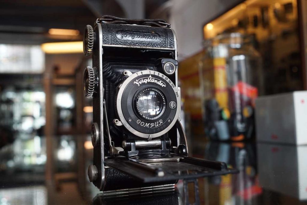 The Voigtlander INOS II is a pre-war 6x9 folding camera that comes with a Heliar 105mm f/4.5 lens in a Compur shutter. The camera rembles the Prominent styling-wise. The focus and transport knob are styled in a knurled way. Shutter fires but is not tested for accuracy. focusing on the camera body does work and turns pretty smooth. Bellows looks good but was not tested for light tightness. A nice collectors camera with a high class lens.