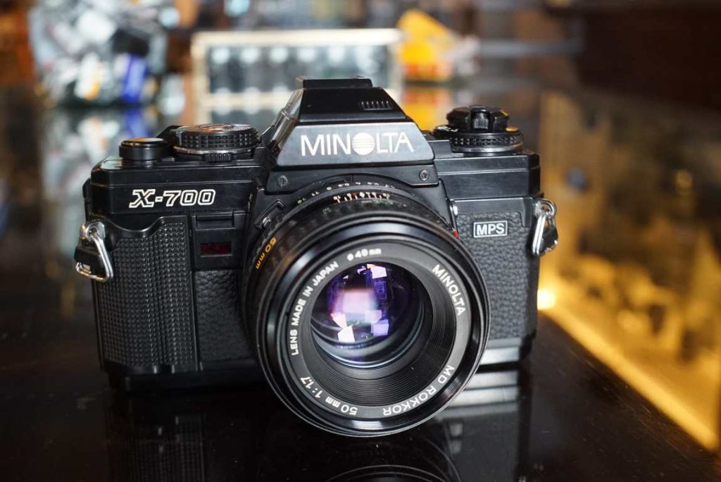 This Minolta X700 comes with a MD Rokkor 50mm f/1.7 standard lens has a bit of a worn appearance but is still working totally fine. The body has some brassing on the prism housing and the overall body has some general wear. The bottom plate is still in good shape and has a protective film installed from new. The light seals have been replaced by us. The shutter works nice and evenly and is accurate on all speeds. The meter also works properly in both manual and automatic modes. The lens is in good shape with smooth focus and aperture is working correctly. Optics are in good shape with just a tiny bit of internal dust. All in all a good user kit.this item comes with a 3 month limited warranty