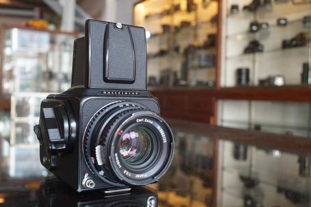 This Hasselblad 500CM is just back from a body service by ACR. The winding mech and aux shutter have been disassembled, cleaned and lubricated. New dampers have been placed. Mirror angle/focus is checked and spot on. The shutter in the lens is tested and found to be perfect on all speeds. Back received new light seals and are ready to go for years. Focus is even throughout range. Setting the aperture/speeds is smooth and works as intended. Good optics, some tiny dust specs inside, no fungus or haze. Nice super bright acute matte focusing screen without focus aid. There are 2 lines for 645 shooting on the screen, a nice free bonus. New style advance crank. Black paint has some regular wear, mainly on the bottom near the tripod socket.this item comes with a 3 month limited warranty