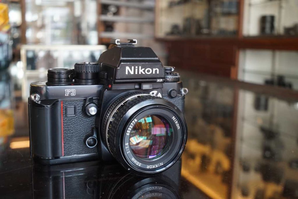 Nikon F3 Press version with some modifications specifically for press photographers and comes with a Nikkor 50mm f/1.4 AI lens. Body has some regular wear and brassing on mostly the top plate edges and a tiny bump near the counter which shifted the red indicator for the counter a tiny but but counter is fully functional. Rubber on shutter button is intact and motor drive cover present. Shutter is accurate on all speeds and the lightmeter gives correct readings too, verified with our Kyoritsu shutter tester. Focusing screen in the camera is a K version with split prism focusing aid. The lens is in very good condition with light wear. Focus turns suprisingly smooth and well dampened. Aperture also works fine and is free from oil. Optics in good shape with just some minimal internal dust. A great kit both interesting for collectors and users as the F3P is pretty uncommon.this item comes with a 3 month limited warranty