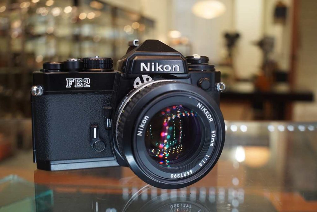 Very beautiful looking Nikon FE-2 in black finish with a Nikkor 50mm f/1.4 AI lens. The camera looks hardly ever used and has only very minimal wear under close inspection. The shutter is accurate on all speeds and the lightmeter responds correctly within margin. Lightseals look fresh so did not need replacing. The Nikkor 50mm f/1.4 AI lens is in very nice shape like the body. Focus does turn a bit heavy, this will likely free up with use. Aperture works properly and no oil on the blades. Optics are in excellent shape with no remarks. A beautiful FE-2 kit that will give you some lovely results.this item comes with a 3 month limited warranty