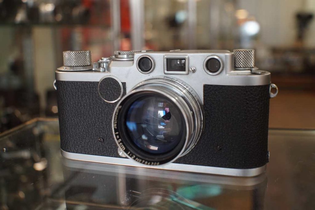 This Leica IIf rangefinder comes in a fully usable condition. They are often found as display-only items, but this copy was restored to good working shape by ACR in 2021. The previous owner, a returning customer of ours, shot some rolls with it but decided to stick with his M4 setup. The camera was fully serviced and received new tape on the shutter curtain. The rangefinder is calibrated and accurate. All speeds are accurate. The leather/vulcanite covers have been replaced by new ones so they will last a long time without crumbling like usual. Lens is cleaned and lubricated (focus and aperture). Good user kit for early Leica rangefinder enthousiasts.this item comes with a 3 month limited warranty