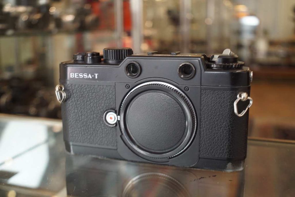 The Voigtlander Bessa T is a Leica M mount rangefinder camera that is mostly meant for use with ultrawide lenses and external finders, but does have a built-in coupled rangefinder which works like a screwmount Leica camera, with a magnified focus spot where you can focus your lens through. The camera also has a built-in lightmeter like the Bessa L does, so in some ways this is a upgraded Bessa L. The camera has some obvious wear, mostly visible on the bottom plate and top cover near the winding crank and back near the lightmeter readout. The shutter is accurate on all speeds on our testing equipment, and the lightmeter also gives correct readings. Great modern and light camera that is definitely something different.this item comes with a 3 month limited warranty