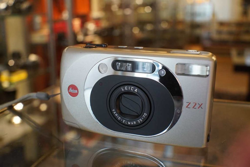 Leica Z2X compact camera produced in the year 2000, complete in original packaging. The front of the body has some obvious wear to the finish, mostly the bottom edge has the paint worn off and the bare plastic shines through it now but it does look very subtle. The camera still works perfectly and the internal flash works fine too. Camera feels responsive to use. Optics are in excellent shape. A nice compact camera to easily take with you.
this item comes with a 2 month limited warranty* (in case the item can not be repaired we will provide a similar item or different solution)