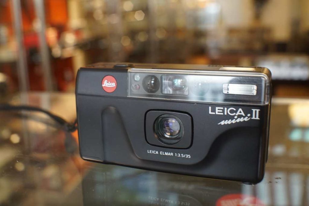 Leica Mini II compact camera with Elmar 35mm f/3.5 wide angle lens, still in good shape with minimal wear. The shutter works correctly and the camera gives correct exposures and the flash works properly. Optically the lens is in excellent shape but the front element does have a slight coating defect on upper side which shows as a reflection. This will not harm pictures made with the lens however. Date back was not tested by us. The camera comes in original packaging as well as a wrist strap.this item comes with a 2 month limited warranty* (in case the item can not be repaired we will provide a similar item or different solution)