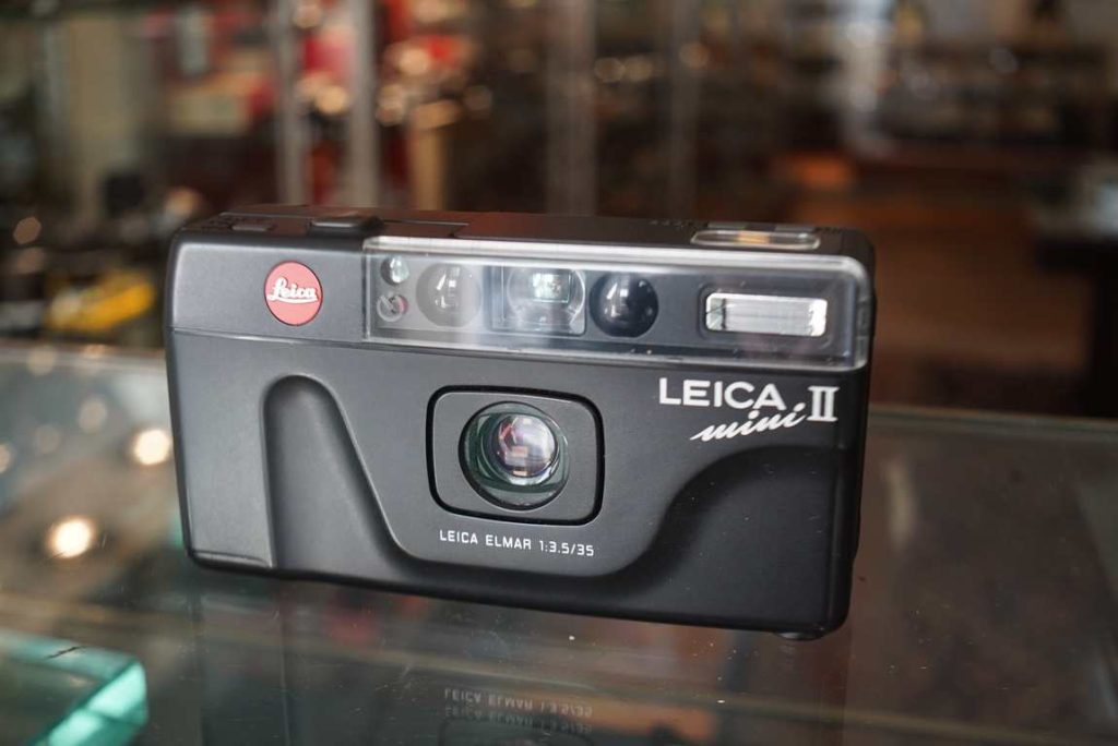 Good working Leica Mini II compact camera with Elmar 35mm f/3.5 fixed lens. The camera was film tested and works perfectly and gives good exposures, even the flash works perfectly. The camera transports properly with good spacing. The camera does sound a bit odd when turning on and focusing but considering the results this does not matter for use at all. Comes in a small case to tranport the camera in. A nice point and shoot camera at a much lower price than a minilux.this item comes with a 2 month limited warranty* (in case the item can not be repaired we will provide a similar item or different solution)