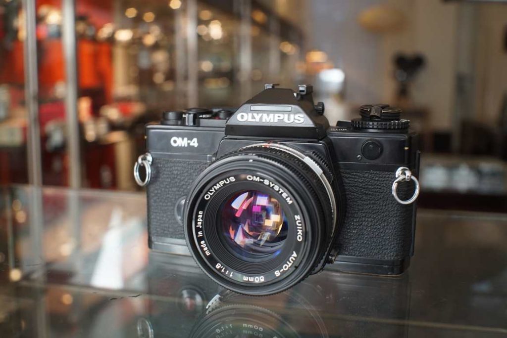 Good working Olympus OM-4 with late MIJ version OM Zuiko 50mm f/1.8 lens The camera body has some paint wear, mostly visible on the corners near the strap lugs, on the edge of the bottom plate and the film door. The rewind crank is slightly bent but still works fine. The shutter is accurate on all speeds and the lightmeter gives correct exposures in both auto and manual modes. The finder image is clear with some minimal dust. The standard split prism focusing screen is installed. Finder information is nice and bright. Light seals have just been replaced. The Zuiko 50mm f/1.8 lens is in excellent shape with smooth turning focus and correct working aperture. No optical issues like haze or fungus. A very nice with very advanced lightmeter capabilities.this item comes with a 3 month limited warranty